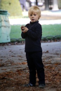 A petit French garcon picking up chestnuts in La Place des Vosges